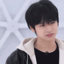 a young man is wearing a black shirt and a white hoodie .