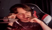 a young man wearing headphones and a microphone is sitting in a chair .