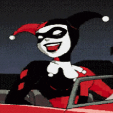 harley quinn is sitting in a red car with her tongue out