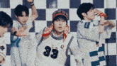 a group of young men are dancing together in front of a checkered background .