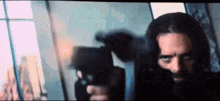 a man with long hair and a beard is holding a gun .