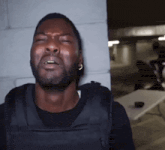 a man wearing a black vest is making a funny face with his eyes closed