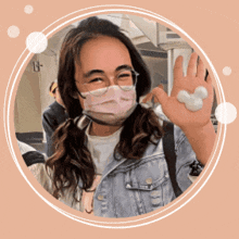 a woman wearing a mask and glasses holds up a mickey mouse shaped object