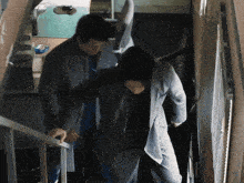 a man in a suit and tie is helping another man up a set of stairs