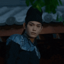 a man is wearing a black hat and a blue shirt .