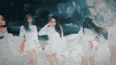 a group of girls in white dresses are standing in the snow