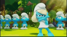 a group of smurfs are standing next to each other in a field .