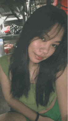 a woman with long black hair is wearing a green shirt
