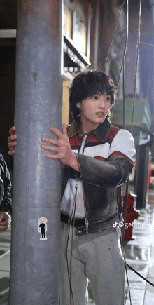 a man in a leather jacket holds onto a metal pole