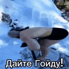 a man is kneeling down in the snow with a shovel .