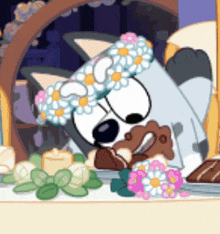 a cartoon dog wearing a flower crown is laying down on a table .