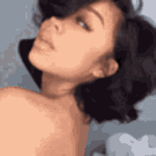 a woman without a shirt is looking at the camera with her eyes closed .