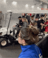 a group of people are riding in a golf cart and one of them is wearing a blue jacket with the number 4 on it