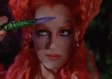 a close up of a woman 's face with red hair holding a knife