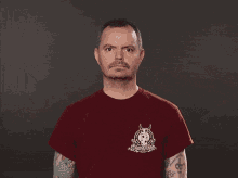a man wearing a red t-shirt with a devil on it shrugging his shoulders