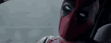 a close up of a deadpool sitting in a car looking out the window .