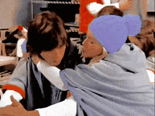 a woman wearing a purple hat is hugging a man