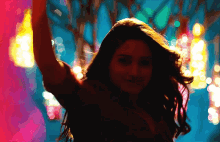 a woman is dancing in front of a blurry background of lights