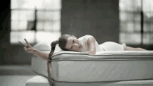 a woman is laying on top of a white mattress .