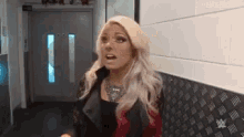 a woman with blonde hair is standing in a hallway with a shocked look on her face .