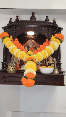 a temple with a statue of a woman surrounded by yellow and orange flowers
