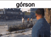 a man in a blue shirt is standing on a sidewalk in front of a building with a sign that says gorson .