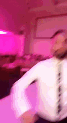 a blurry picture of a man dancing in a room with pink lights