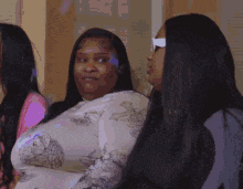 a group of women are sitting next to each other and one of them is wearing sunglasses .