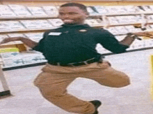 a man in a black shirt and khaki pants is jumping in a store .