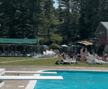 a group of people are sitting around a swimming pool with chairs and umbrellas