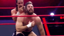 two men are wrestling in a ring and one of them is wearing a bandage on his chest .