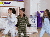three women in pajamas are dancing in front of a quicksleep mattress