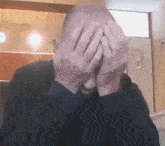 a man covering his face with his hands in a kitchen