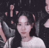 a girl with a tattoo on her face is looking at the camera while two other girls are standing behind her .