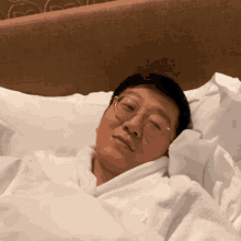 a man wearing glasses is laying in bed