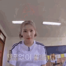 a girl in a white shirt is sitting in a classroom with korean writing on the wall .