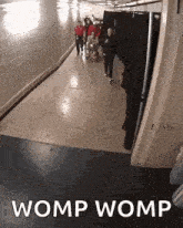 a group of people walking down a hallway with the words womp womp