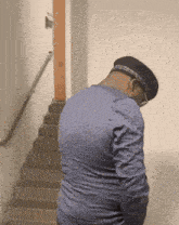 a man wearing glasses and a hat is walking down stairs