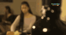 a blurred image of a woman sitting on a couch with a sign that says ' kapuso online live '