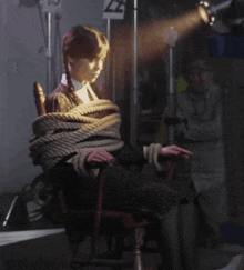 a woman is tied up in a chair with a sign that says z2 on it