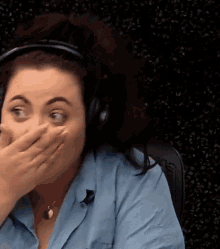 the woman is wearing headphones and covering her mouth with her hand