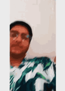 a man wearing glasses and a hat is taking a picture of himself .