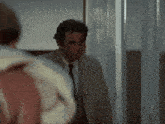 a man in a suit and tie is walking through a hallway