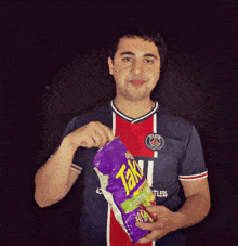 a man is holding a bag of takis chips