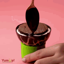 a spoon is being used to spread chocolate sauce on an ice cream cone