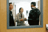 a man and a woman are talking in a room with a glass door