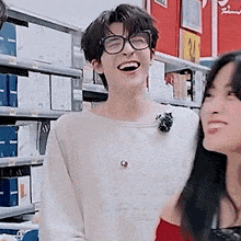 a man wearing glasses is laughing with a woman in a store .