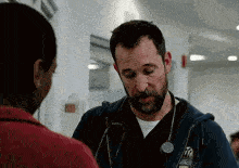 a man with a beard is talking to a woman in a hospital .