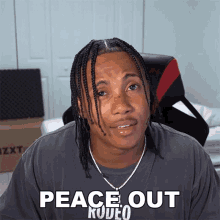 a man with braids is wearing a gray shirt that says peace out rodeo