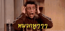 a man is holding his head with his hands and making a shocked face .